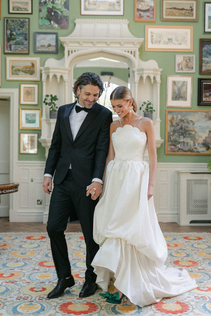 bride and groom holding hands while walking in green room at Oakley Court Windsor