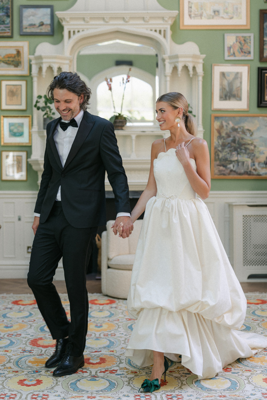 bride and groom holding hands while walking in green room at Oakley Court Windsor