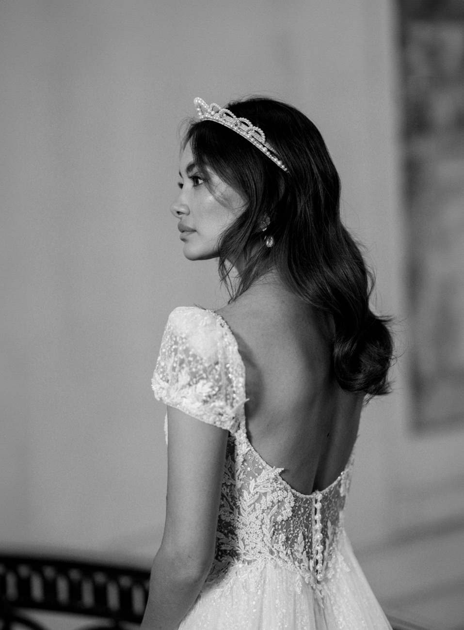 bride standing with princess headband and low back beaded wedding dress